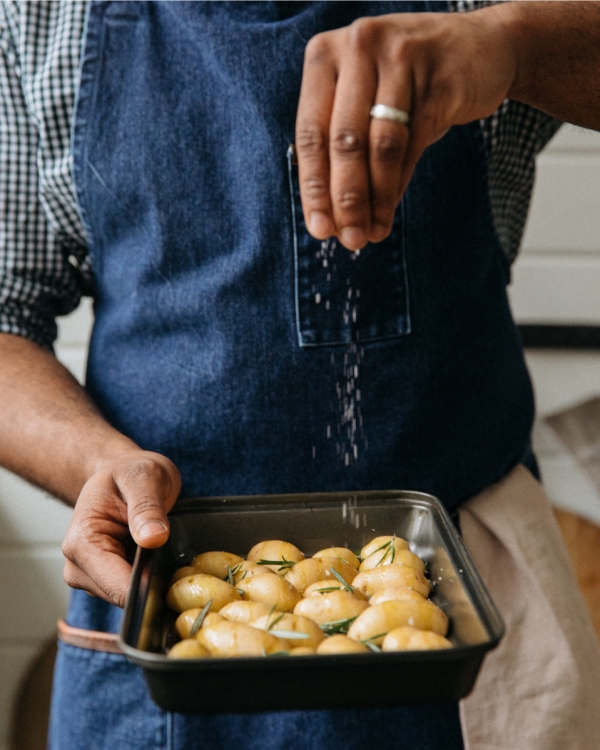 A chef sprinkling salt over some potatoes at Saint Bibiana